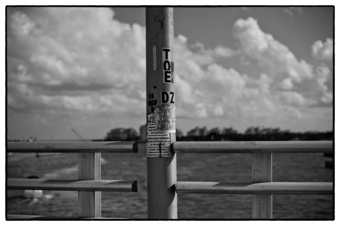 This shot was captured by famed german photographer/ graffiti street art historian/ photojournalist   Ruediger Clatz while crossing the small bridge that leads to the entrance of South Beach and over looks the beautiful ocean by the Port of Miami. My wheat pasted faded logo poster I put up during last year's Art Basel, Still up and running in its Prime Location. Thanks Ruedi